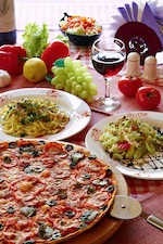 Classic Italian food setting with pizza, pasta, salad and wine