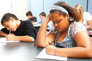 Classroom of diverse students taking objective testing in school.