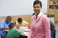 Students In Class Writing With Teacher In Foreground (Selective Focus)