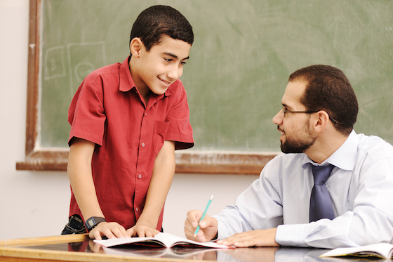 Teacher helping pupil in classroom to resolve schoolwork