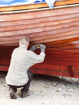 man repairing his old boat at marina