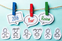 Paper speech bubbles with text 2016 Year Review hanging on the line with some paper people under