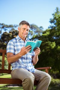 Casual man reading in the park on a sunny day